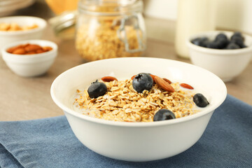 Tasty oatmeal with milk, blueberries and almonds in bowl on table, closeup