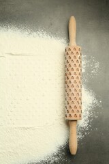 Wooden rolling pin and flour on grey table, top view