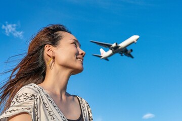 青空の下で飛行機を眺める女性