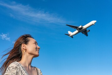 青空の下で飛行機を眺める女性