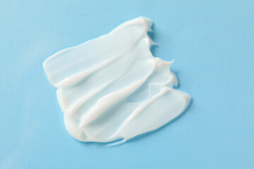 Sample of body cream on light blue background, top view