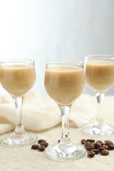Coffee cream liqueur in glasses and beans on white textured table