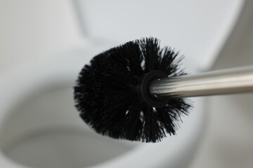 Black toilet brush and bowl indoors, selective focus