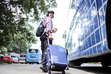 Full Body Of Traveler Asian Guy In Casual Style With Backpack And Suitcases Walking On Bus Station