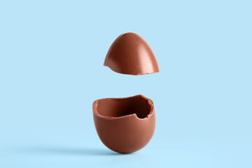 Broken chocolate egg flying on blue background