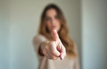 Blurred image of woman extending finger at camera. Hand indicates direction, touching, pushing virtual screen. Focus on index finger. Concept of choice, selection, invitation, communication,