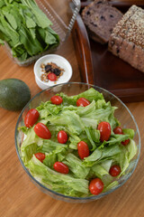 A vibrant, refreshing salad of crisp lettuce and ripe tomatoes served in a large bowl, perfect for sharing in the center of the table. This wholesome, light dish is an ideal accompaniment for a family
