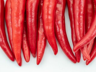 Close-up of vibrant red chili peppers on a white background showcasing their texture and color.