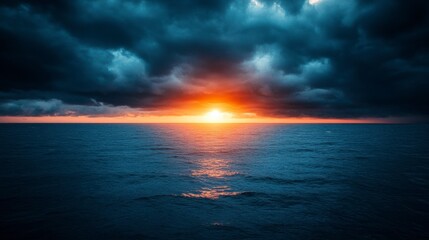Fototapeta premium Dark stormy clouds over a calm ocean at sunset. Orange and dark blue hues dominate the scene. The sun sets on the horizon, casting a reflection on the water.