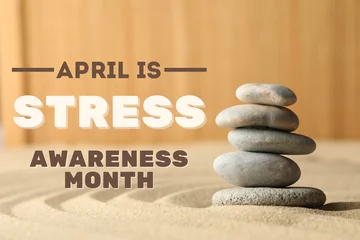 Stress month, balancing stones on sand on wooden background with text