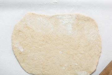 Overhead view of rolled out crackers dough on parchment paper, cracker biscuit dough on white...
