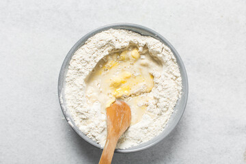 Overhead view of doughnut dough being mixed in a grey mixing bowl, top view of doughnut dough on a white countertop, process of making doughnut