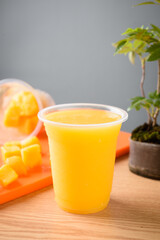 Mango smoothie in plastic cup on orange tablecloth
