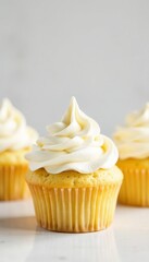 Delicious vanilla cupcakes topped with smooth whipped cream against a blank backdrop, vanilla, treat