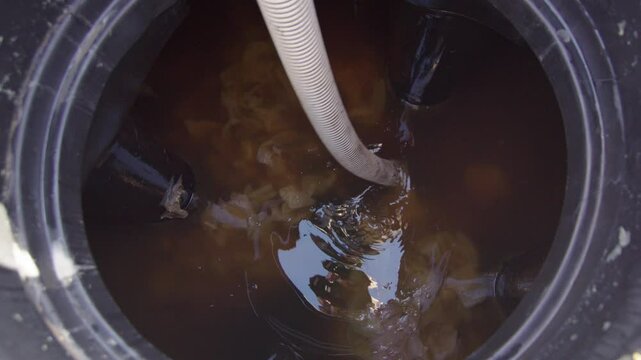 Top view of a suction pipe emptying a closed septic sewage tank