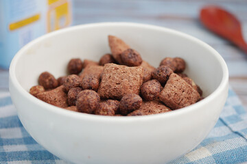 Bowl of assorted chocolate cereal against a wooden background
