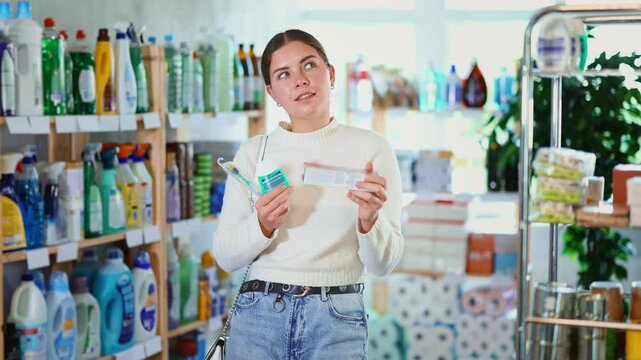 Young European woman chooses a toothbrush, toothpaste and mint oral cleanser. Store visitor buys a dental care kit. High quality 4k footage
