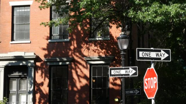 New York City oneway crossroad, Stuyvesant street intersection one way arrow. Manhattan Midtown residential building architecture, United States real estate. Red brick house wall, red stop road sign.