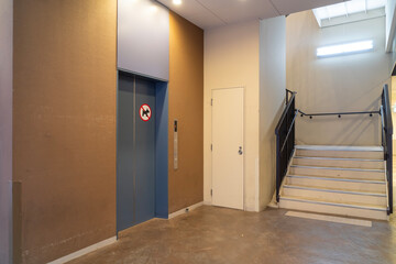 The elevator entrance has a no-dog sign, a closed door, and stairs to create a contemporary atmosphere.