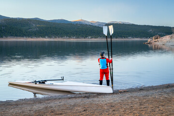 male rower and a coastal rowing shell on a rocky shore of Carter Lake in fall or winter scenery in northern Colorado. © MarekPhotoDesign.com