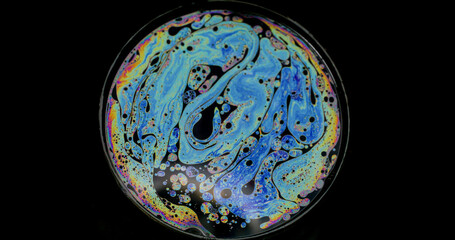 Rainbow sphere. Oil pigment. Colorful round lens on black background. Abstract floating gasoline neon paint blend fluid surreal surface.