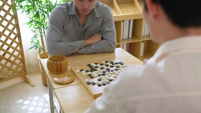 Asian young men playing board game Go during competition in community. 