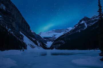 A frozen lake nestled between snow-covered mountains under a starry night sky. Captures a serene and dramatic winter landscape