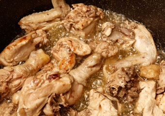 A pan of chicken is cooking in a pan with oil