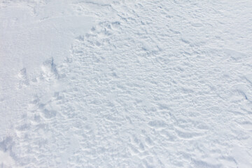 A snow covered ground with a few footprints