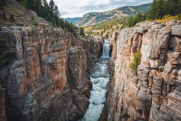 Naklejka premium A majestic waterfall cascading through a rugged rocky canyon landscape