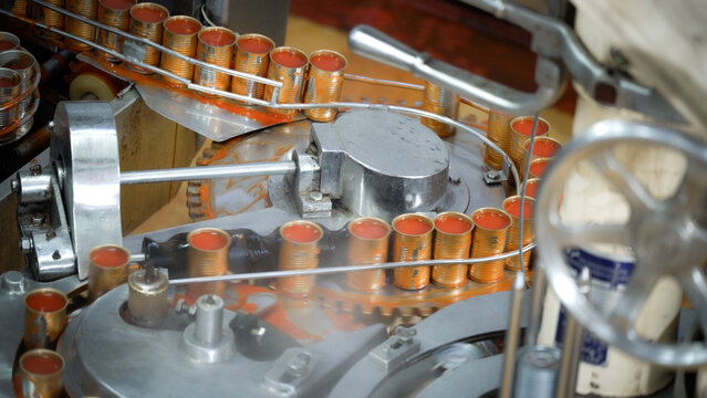 The machine is producing a large number of canned food products containing red liquid.
