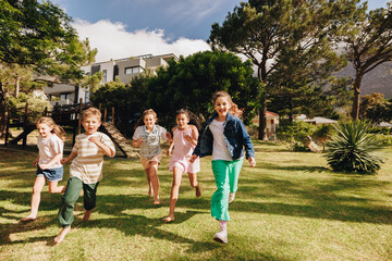 Obraz premium Children running and playing outdoors on a sunny day in a yard