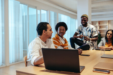 Fototapeta premium Informal company meeting with diverse staff having a collaborative discussion in a modern office setting