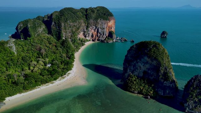 Experience the breathtaking beauty of Thailands coastline, featuring vibrant emerald waters, striking rock formations, and lush green foliage. Railay beach krabi