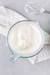 Whipped egg whites in a bowl for baking on kitchen table