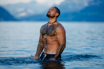 Shirtless muscular man swimming in a lake. Handsome athlete enjoying water in nature. Fit male...