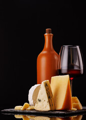 A refined selection of aged cheeses presented on a board, accompanied by a glasses of wine