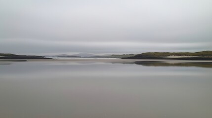 Fototapeta premium Serene Coastal Landscape Calm Waters Reflecting a Cloudy Sky and Distant Hills