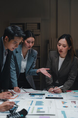 Asian businesspeople working late analyzing financial charts in office meeting room