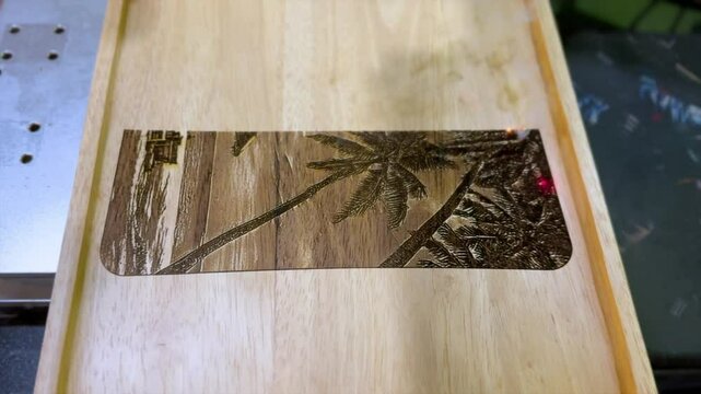 Laser engraving palm tree design on a wooden surface