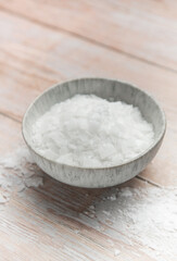Magnesium chloride flakes in a bowl on rustic wooden table