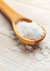 Wooden spoon holding magnesium chloride flakes on white table