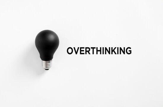 Black light bulb representing overthinking placed on white background