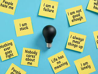 Switched-off Lightbulb Surrounded by Negative Sticky Notes Expressing Depression and Anxiety