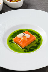 Sous-vide salmon fillet with fish roe, garnished with sorbet and microgreens, served on a vibrant green herb sauce
