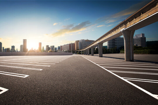 Sunset scene empty parking lot under the train monorail railway with city background.