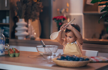 Happy Toddler Cooking and Playing in the Kitchen with a Wooden Spoon