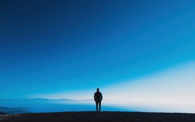 A person stands atop a mountain, gazing at the vast ocean below.