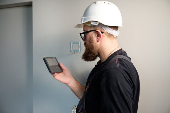 Security alarm installation. Security technician installing safe monitor on wall in the new office. Installing security system. Man worker installing alarm technology insurance in home