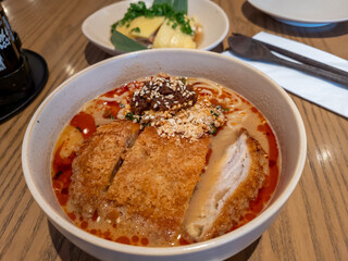A bowl of hot chilli spicy hand pulled noodles soup served with fried port chop in a crispy coating.